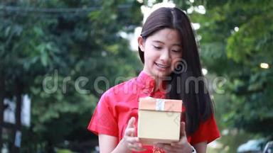 泰国少年漂亮女孩穿着<strong>中国服装</strong>，新年快乐，打开盒子礼物，微笑和非常高兴。